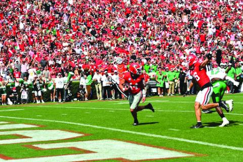 Wesley Branch/The Clayton Tribune. Georgia quarterback Gunner Stockton evades a Marshall defender on his way into the end zone in Georgia’s 45-7 season-opening win on Aug. 30. The former Rabun County standout threw two touchdown passes and ran for two more as the Bulldogs’ No. 1 starting QB.
