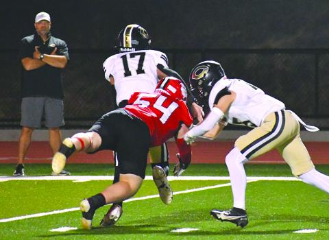 Enoch Autry/The Clayton Tribune. Commerce City School System Superintendent Billy Kirk (far left) watches as Wildcat Ryan Yearwood makes a hit on Commerce quarterback Tate Kirk, the superintendent’s son. The elder Kirk would be ejected from the game in the third quarter. RCHS won 55-28.