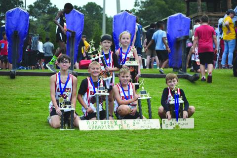 Submitted Photo. Rabun County high-point top-five champions are Caiden Wood, Kai Hanifan-Wagner, Owen Mosely, Keegan Hanifan-Wagner, Nora Webb and Opal Aker sit on the grass with their trophies at the concluson of the district championship at Athens Christian School. 