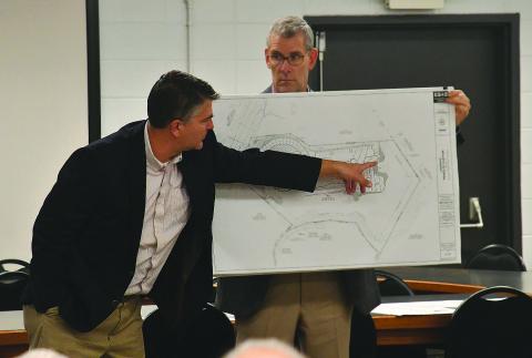 Enoch Autry/The Clayton Tribune. With Gary Hammond Jr., developer/owner of Landbridge Development holding the rendering, Matt Kriete of Engineering, Survey and Services, Inc., points out the location where the parking spots would go on the property at the future Peaks of Clayton housing project.
