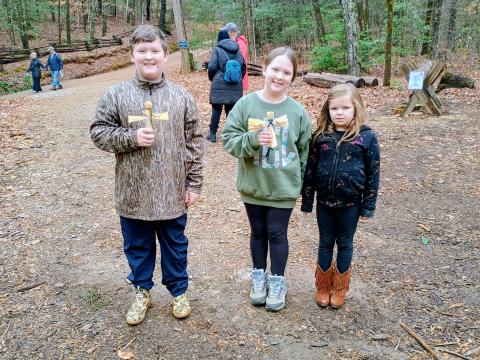 Megan Horn/The Clayton Tribune. Bentley Conner, 10; Ava Conner, 9; and Harper Mashburn, 6, enjoy their time at “A Foxfire Christmas” last weekend. The kids are holding corn husk dolls, one of many crafts made during the event. 