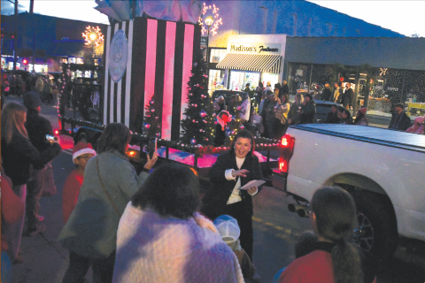 Enoch Autry/The Clayton Tribune. Madison’s on Main won “Best Overall Float” for its giant shopping bag that was among the entries that rolled down Clayton’s Main Street for the annual Christmas Parade. In the background is the business that is located at 41 Main Street. Thousands attended the Dec. 6 event with lighted floats.