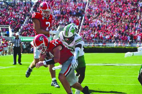 Wesley Branch/The Clayton Tribune. Former Rabun County and current UGA quarterback Gunner Stockton fights off defenders for a rushing touchdown in Georgia’s 45-7 season-opening win over Marshall on Aug. 30, 2025. Stockton, who finished seventh in Heisman voting this season, will return to Georgia for his redshirt senior season in 2026. 