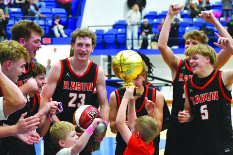 Wesley Branch/The Clayton Tribune. Reeves Page hoists the Battle of the States championship trophy while he and Cal Burrell (left center) celebrate with the Rabun County boys basketball team on Dec. 30 after its 64-59 win over Chesnee. The Wildcats will be at home again on Jan. 13 versus Athens Academy. 
