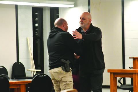 Enoch Autry/The Clayton Tribune. Retiring Clayton Police Chief Andy Strait shakes the hand of new city council member Channing Watts at the conclusion of Tuesday night’s meeting. Colt Woodall (far left) and Mayor Pro Tem Stacy Fountain watch..