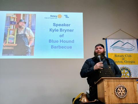Megan Horn/The Clayton Tribune. Kyle Bryner, owner of Blue Hound Barbecue in Dillard, speaks to Rotary Club of Clayton members about his passion for cooking during the Jan. 8 club meeting. 