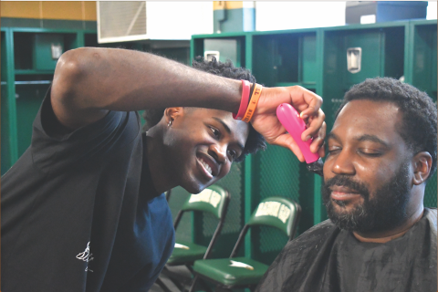 Wesley Branch/The Clayton Tribune. A smiling Rabun Gap senior RJ Lacossade from Turks and Caicos cuts Rabun Gap boys assistant basketball coach Darrick Cureton’s hair in the Rabun Gap-Nacoochee School locker room on Jan. 12. Lacossade has been cutting hair for several years now, cutting his own hair and other students at RGNS. 