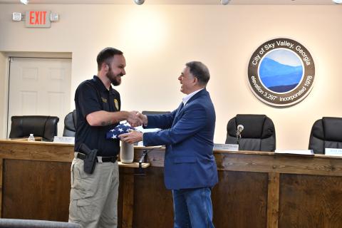 Megan Horn/The Clayton Tribune. U.S. Rep. Andrew Clyde of Georgia’s Ninth District, right, presents Sky Valley Police Officer Andrew Williams with a flag that was flown over the U.S. Capitol and a certificate designating him as a “Special Georgian of the Ninth” during a special event on Feb. 19 in Sky Valley. Williams was honored by Clyde for rescuing a couple from a Jan. 22 Sky Valley structure fire. 