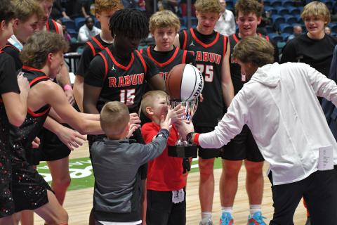 Wesley Branch/The Clayton Tribune. RCHS head coach David Adcock hands the state championship trophy and basketball to Cal Burrell and Reeves Page as senior Colton Crane (left) moves in to help the “goons” lift the two important pieces of hardware. 
