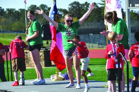 Wesley Branch/The Clayton Tribune. Adrian Appleby (center) dances on the stage with buddy and Rabun County High School student Bella Hulsey after receiving a medal at the Rabun County Special Olympics on April 2 at Frank Snyder Memorial Stadium. Also on the stage receiving medals as photographed above are athletes Truett Beck (right) and Jonathan Chapman (left) with buddies Katelynn Duncan and Chloe Shirley. 