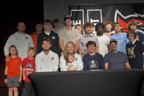 Wesley Branch/The Clayton Tribune. Rabun County senior Huey Blalock (center, right) poses with his family and the RCHS boys basketball team after signing his letter of intent to Navy on April 30 at the Rabun County High School Fine Arts Building. Blalock led the Wildcats to their first ever state title this season. 