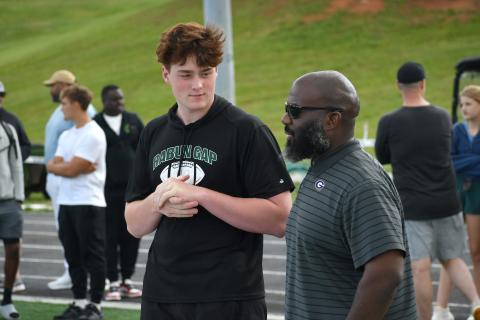 Wesley Branch/The Clayton Tribune. Rabun Gap class of 2027 defensive lineman Marcellus Young Casario talks with Georgia defensive line coach Tray Scott during the Rabun Gap spring college coaches social on Rabun Gap’s campus May 7. Casario has scholarship offers from Georgia, Georgia Tech, Michigan State and others. 