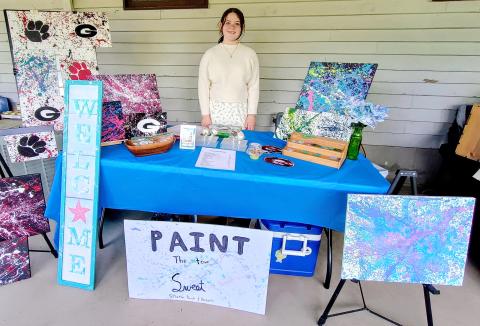 Megan Horn/The Clayton Tribune. Evelyn Raines, 12, with the business “Paint the Town Sweet” was excited to see many visitors to the third annual EdVentures Resource Center Kids’ market last week. The business features paintings and homemade baked goods. 