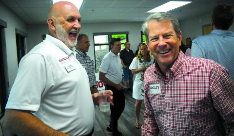 Enoch Autry/The Clayton Tribune. Clayton Mayor Roy Quilliams shares a laugh with Gov. Brian Kemp after the governor puts a Dooley for U.S. Senate sticker on Quilliams’ shirt at the May 29 Meet & Greet in Rabun County.