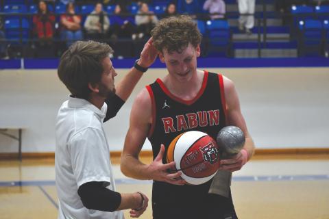 Wesley Branch/The Clayton Tribune. Rabun County head boys basketball coach David Adcock (left) presents RCHS senior Hayes Free with a commemorative ball for scoring his 1,000th career point after the Wildcats’ win over Chesnee (S.C.) on Dec. 30. Free recently announced his commitment to Young Harris College.