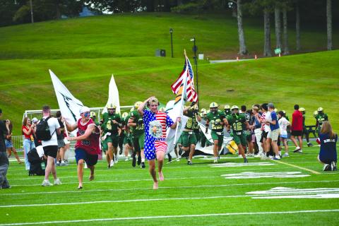 Enoch Autry/The Clayton Tribune. With junior tight end Cash Washburn carrying the American flag, Rabun Gap runs onto the field on a night the 9/11 attack was remembered.