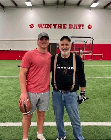 Photo via @gstockton14 on Instagram. Gunner Stockton (left) poses for a photo with George Bobo on Stockton’s signing day in December 2021. Stockton began training with Bobo at age 6 and now plays for his son and University of Georgia offensive coordinator Mike Bobo and with grandson Drew Bobo, Georgia’s starting center. 