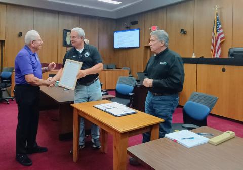 Megan Horn/The Clayton Tribune. Vietnam Veteran Bruce Gant, left, is presented with the framed proclamation from Commissioner Kent Woerner designating Rabun County as a “Purple Heart County.” Gant is a two-time Purple Heart Recipient and was honored at the meeting along with Purple Heart recipient Roy DeFoor. Commission Chairman Greg James called the men heroes. 