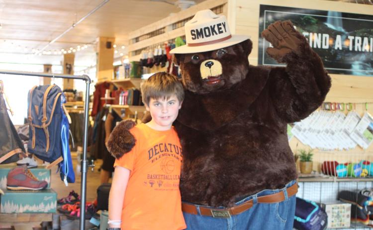 Megan Broome/The Clayton Tribune. Wiley Perreault, 10, poses with Smokey Bear at Wander North Georgia on Monday. Representatives of the Georgia Forestry Commission walked around downtown Clayton to educate the community on fire risk during a drought and how to prevent wildfires.