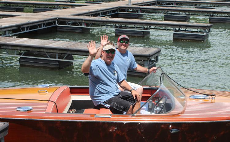 Megan Broome/The Clayton Tribune.Fred Beck, left, and Hunter Hargrave showcase Beck’s 1959 Chris Craft wooden boat named “Tallulah” at LaPrade’s Marina following Lake Burton’s first-ever Wooden Boat Parade. The whole boat is completely original and has been on Lake Burton its entire life.
