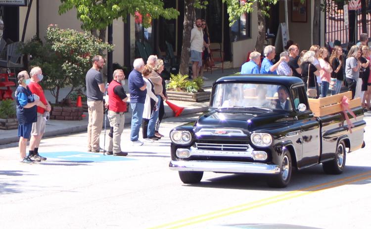 Megan Broome/The Clayton Tribune. The body of Lewis Reeves, Jr. was taken past Reeves Hardware a final time Saturday in a restored Reeves pickup truck as employees and members of the community pay their respects.
