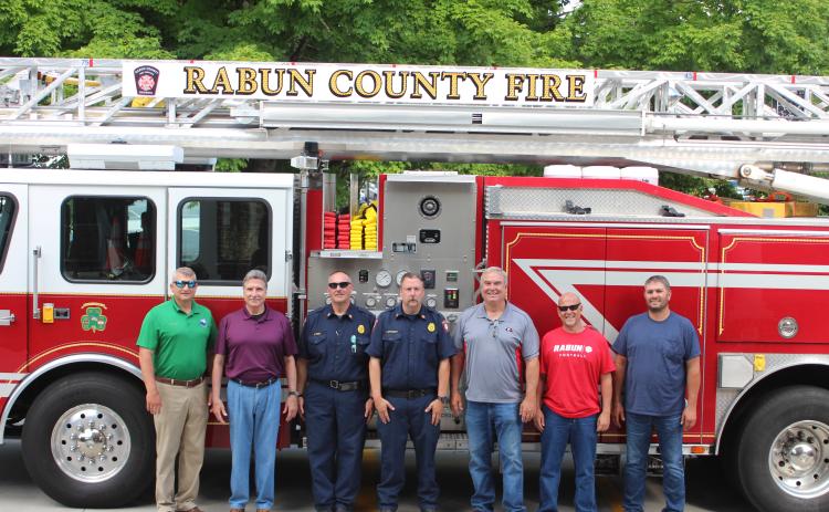 Megan Broome/The Clayton Tribune. Rabun County Fire Services put the county’s first ladder truck into service recently. It responds to fire and rescue calls across the county. Pictured from left are Darrin Giles, county administrator, Greg James, commissioner chairman, James Reed, fire chief, Justin Upchurch, assistant fire chief, and Commissioners Kent Woerner, Scott Crane and Will Nichols.