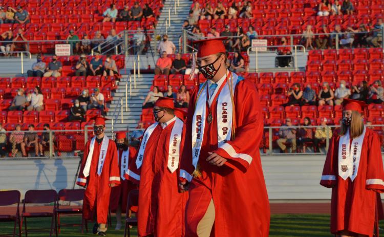 Wayne Knuckles/The Clayton Tribune. Under fair skies and a nearly-full moon, the Rabun County High School Class of 2020 received diplomas Saturday at Frank Snyder Memorial Stadium. Pictured: Andrew O'Brien, left, Cole Littrell and Will Hightower take their places.