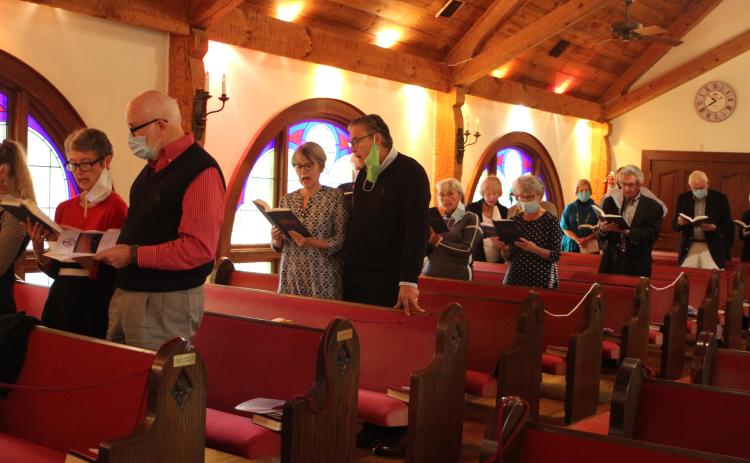 Megan Broome/The Clayton Tribune. The congregation stands and sings hymnals at a church service and special 40th Anniversary celebration of the Tom McClure Memorial Chapel in Sky Valley Sunday.