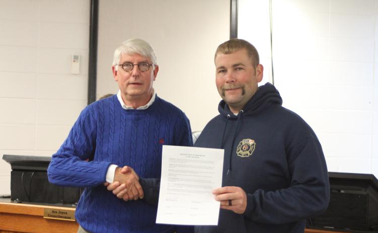 Megan Broome/The Clayton Tribune. Clayton Mayor Jordan Green and Clayton city council members signed a resolution to proclaim that whatever day on which the city of Clayton Christmas parade takes place is hereby declared “Carl Butler Day.” Butler, left, shakes hands with Jordan Green after the city adopted the resolution at Tuesday’s council meeting.