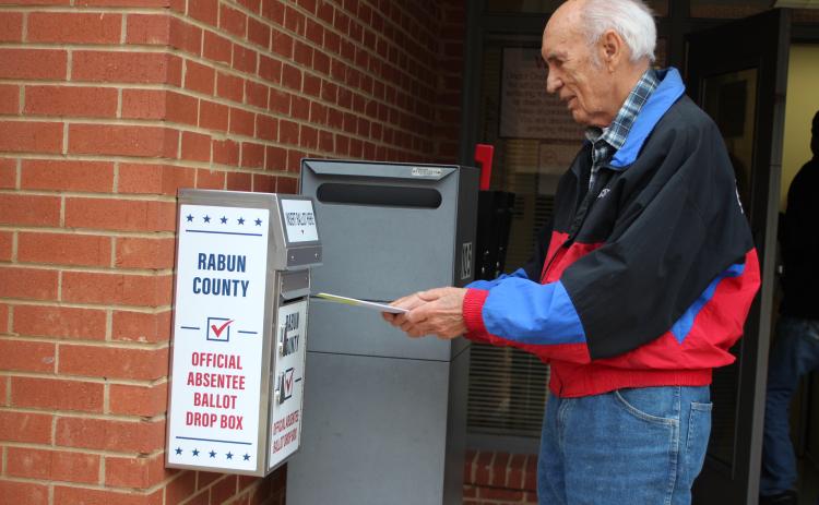 Megan Broome/The Clayton Tribune. Voter J.P. Miles returns his absentee ballot to the designated box in front of the Board of Elections Office on Monday. The office is located at 18 Old Raco Dr., Suite 105, Clayton.