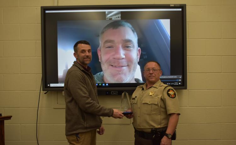 Photo courtesy Rabun County Sheriff’s Office. Chief Deputy Scott Cheek, left, presents the Deputy of the Year award to Deputy Tony Parrish in December. Sheriff Chad Nichols participates via video call.