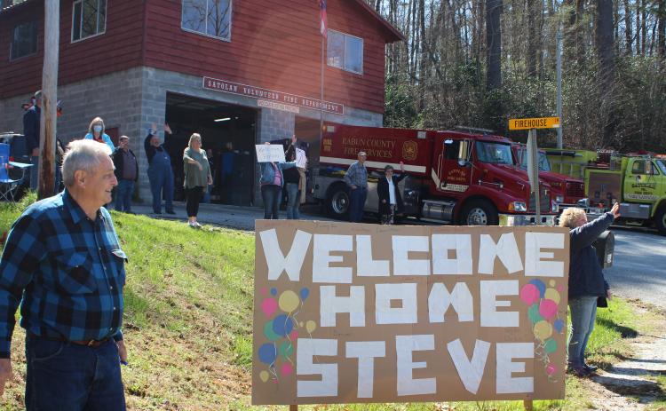 Megan Broome/The Clayton Tribune. Friends and family of former Satolah Fire Department Chief Steve Wilson gathered at the Satolah Fire Station Tuesday to welcome him home after a months-long battle being hospitalized with COVID-19. Jimmy Nix stands beside the homemade sign and cheers for Wilson along with other friends and family members.