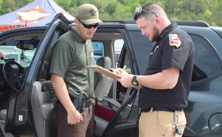 Megan Broome/The Clayton Tribune. Rabun County Sheriff's Office Patrol Corporal Clinton Scott, left, and Dillard Police Chief Jeremy Parker participated in a car seat inspection event at the Clayton Walmart recently where nationally certified technicians helped citizens properly install car seats and booster seats. The RCSO partnered with Safe Kids Rabun County for the event. Scott was one of five deputies who became certified as a Child Passenger Safety Technician (CPST).