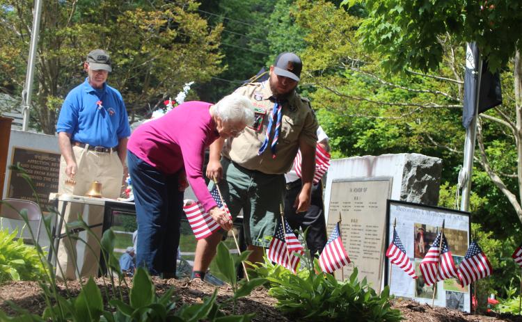 Megan Broome/The Clayton Tribune. Wilma Hoilman places a flag to honor the memory of a veteran close to her who has passed away at Monday’s Memorial Day ceremony. Also pictured are Col. (Ret.) Guy Gober, who was the guest speaker, left, and Eagle Scout Dominic Cross.