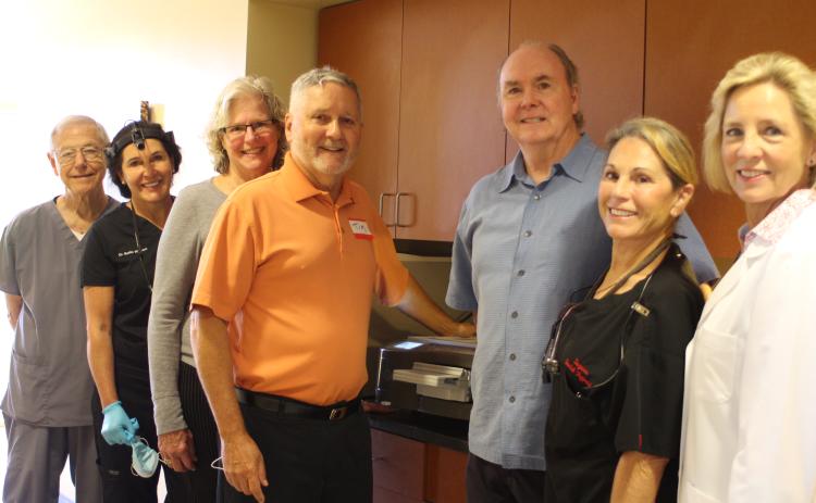 Megan Broome/The Clayton Tribune. Dr. Tom Callahan, left, Dr. Mollie Winston, Jane Janes, Tim Ranney, Dick Newkirk, Suzanne Newkirk and Dr. Janet Dunwoody stand in front of the new flash sterilizer in the Community Dental Clinic at the Rabun County Health Department.