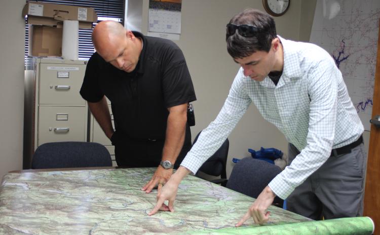 Megan Broome/The Clayton Tribune. Brian Panell, new EMA director, left, and Troy Keenan, head of the Rabun County mapping department, look over a map of an area of Rabun County and brainstorm ideas of how to improve radio communication in the area.