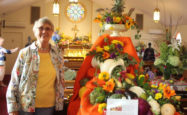 Megan Broome/The Clayton TribunePeggy Melton stands in front of a floral arrangement . depicting “God’s Bounty” at the 14th annual Flower Festival at St. James Episcopal Church on Saturday.  The theme was “God’s Creation: Behold, I make all things new” and floral arrangements were created to represent and celebrate God’s creations.