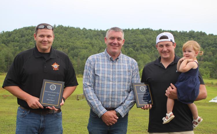 Megan Broome/The Clayton Tribune. Sheriff Chad Nichols, center, presents the Bravery Award to Deputy Jeffrey Hooper, left, and the Life Saving Award to Deputy Brandon Hyer for their roles in going above and beyond their normal duties to help citizens and save lives. Hyer holds his daughter, Blakely Hyer.