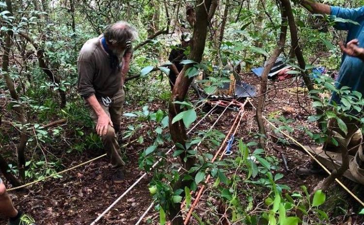 Submitted photo. Buzz Williams, a Chattooga Conservancy program associate, foreground, observes as an antique hand-carved wooden canoe is lowered down a ridge.