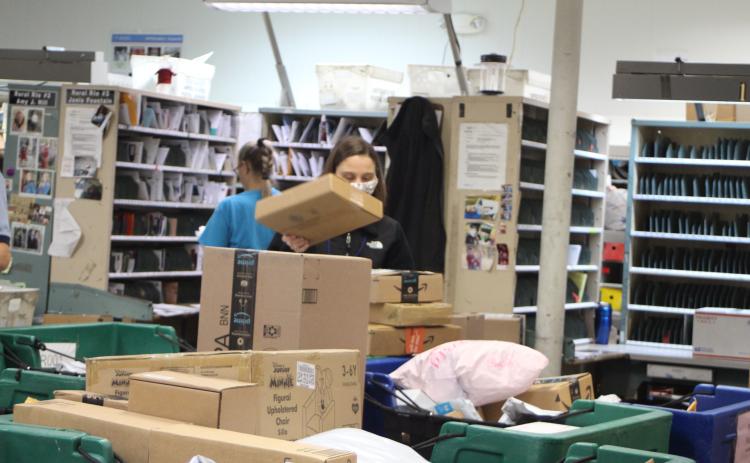Megan Broome/The Clayton Tribune. Amanda Noffsinger sorts packages at the Clayton Post Office on Monday. The post office is receiving a higher volume of packages than usual for this time of year, receiving an average of 1,000 packages each day, according to Colby Nichols, acting supervisor for the Clayton Post Office.