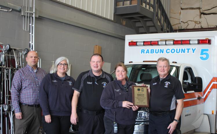 Megan Broome/The Clayton Tribune. Retiring EMT-I Stephanie Quilliams receives her honor from Mike Carnes, EMS/911 director (far right). Standing next to Quilliams, who retires with 26 years of service, are Lt. Brian Panell, Lt. Tammy Jones, and Capt. Trampes Stancil.