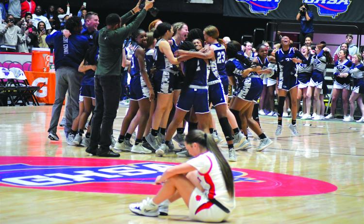 Enoch Autry/The Clayton Tribune. As Rabun County Ladycat senior Sophie Woodard sits on the court floor, the Elbert County Lady Blue Devils, cheerleaders and fans celebrate the school's first-ever state girls basketball championship on March 10.