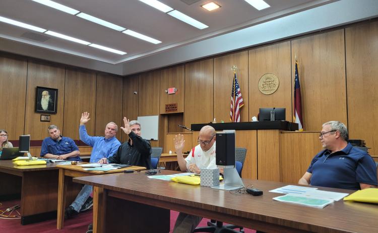 Megan Broome/The Clayton Tribune. A rezoning request for a 20.15 acre property off of Highway 76 East from Agricultural (A) to Commercial Business (CB) for the purpose of building storage units was denied by Commissioners in a 3-2 vote at Tuesday’s meeting. Kent Woerner, Greg James and Scott Crane show their hands in favor of the motion to deny the rezoning, while Will Nichols and Tom Garrison voted in opposition to the motion.
