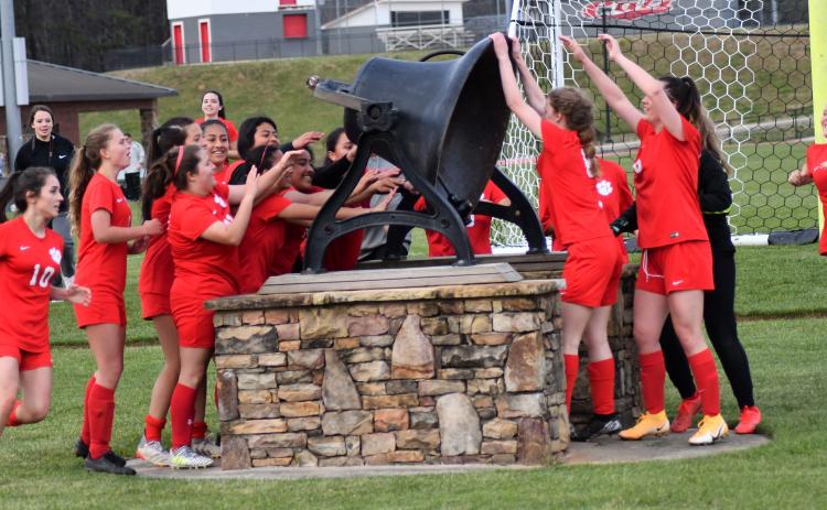 Enoch Autry/The Clayton Tribune. A smiling group of Ladycats ring the bell at the stadium after a 6-0 victory over the Lady Blue Devils.