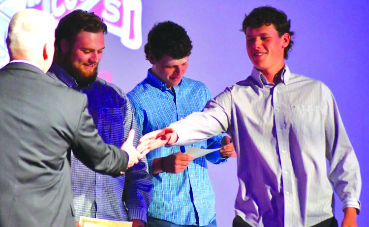 Enoch Autry/The Clayton Tribune. With his twin brother Conner Horton in the background, Garrett Horton receives his senior honors night recognition Tuesday as the Hortons were honored by RCHS athletic director Jason Gibson for signing golf scholarships to play at the University of North Georgia.