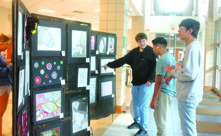 Megan Broome/The Clayton Tribune. Seniors Kane Collins, Ishy Duran and George Juarez browse the Rabun County High School Student Art Show held in the Fine Arts Building May 13. The show featured artwork from students in grades 9-12.