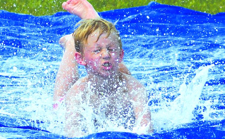 Enoch Autry/The Clayton Tribune. With some of the hottest days this year statewide, Rabun County outdoor summer youth camps have been challenged in finding ways to keep participants cool. Here, Cowen Gilbert, does a head-first slide on a tarp soaked with water and dish detergent during the last day of the Wildcat Baseball Camp on June 16.