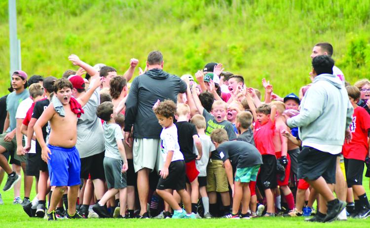 Enoch Autry/The Çlayton Tribune. With RCHS head coach Michael Davis (center) leading the group, the football campers react to an evening of fun on the field.