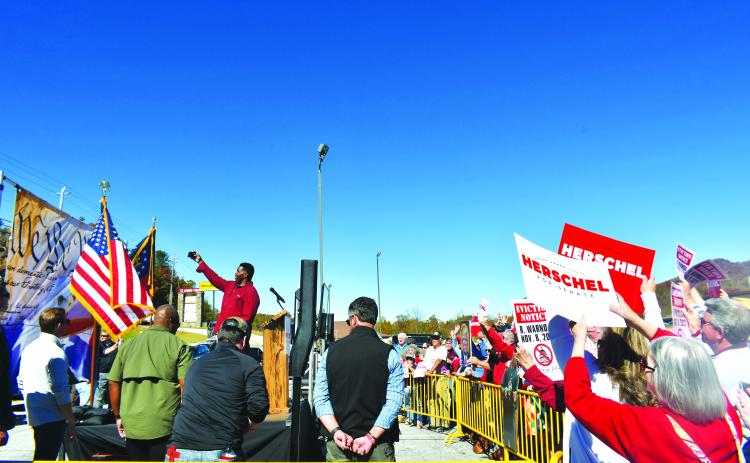 Megan Broome/The Clayton Tribune. On his visit to Rabun County, U.S. Senate candidate Herschel Walker takes a selfie with a gathering of attendees holding up campaign signs for the former football standout turned candidate. Walker faces Democratic incumbent Rev. Raphael Warnock in one of the most highly watched races in the nation.