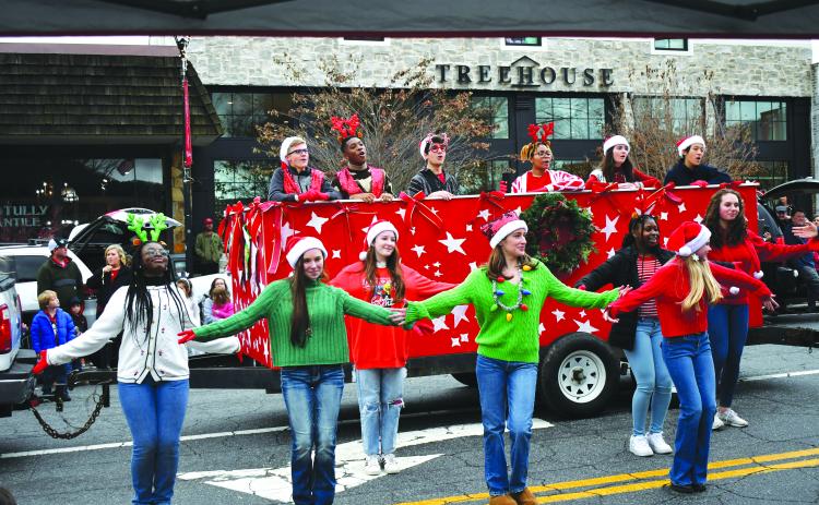 Enoch Autry/The Clayton Tribune. Rabun Gap-Nacoochee School students sing and dance to Christmas music at the annual Clayton downtown parade on on Main Street on Dec. 3. Singing from the float (from left) are Tyler Price, Chidera Onyia, Cyrus Manoogian, Sharra Rolle, Vivi Diaz and Vivian Guo. The dancers (from left) are Blaire Lauder-Williams, Elizabeth Brenner, McKenna Bilbrey, Anni Geren, KayKay Justilien, Abigail Brenner and and Emma Jenkins.